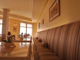 Un rincón comedor con un sofá a rayas, una mesa de comedor con sillas y un ventanal grande.