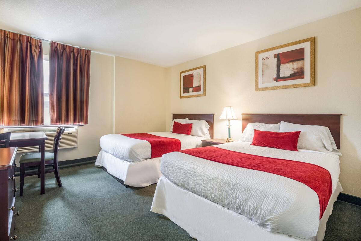 Une chambre d’hôtel avec deux lits, un bureau et une chaise.