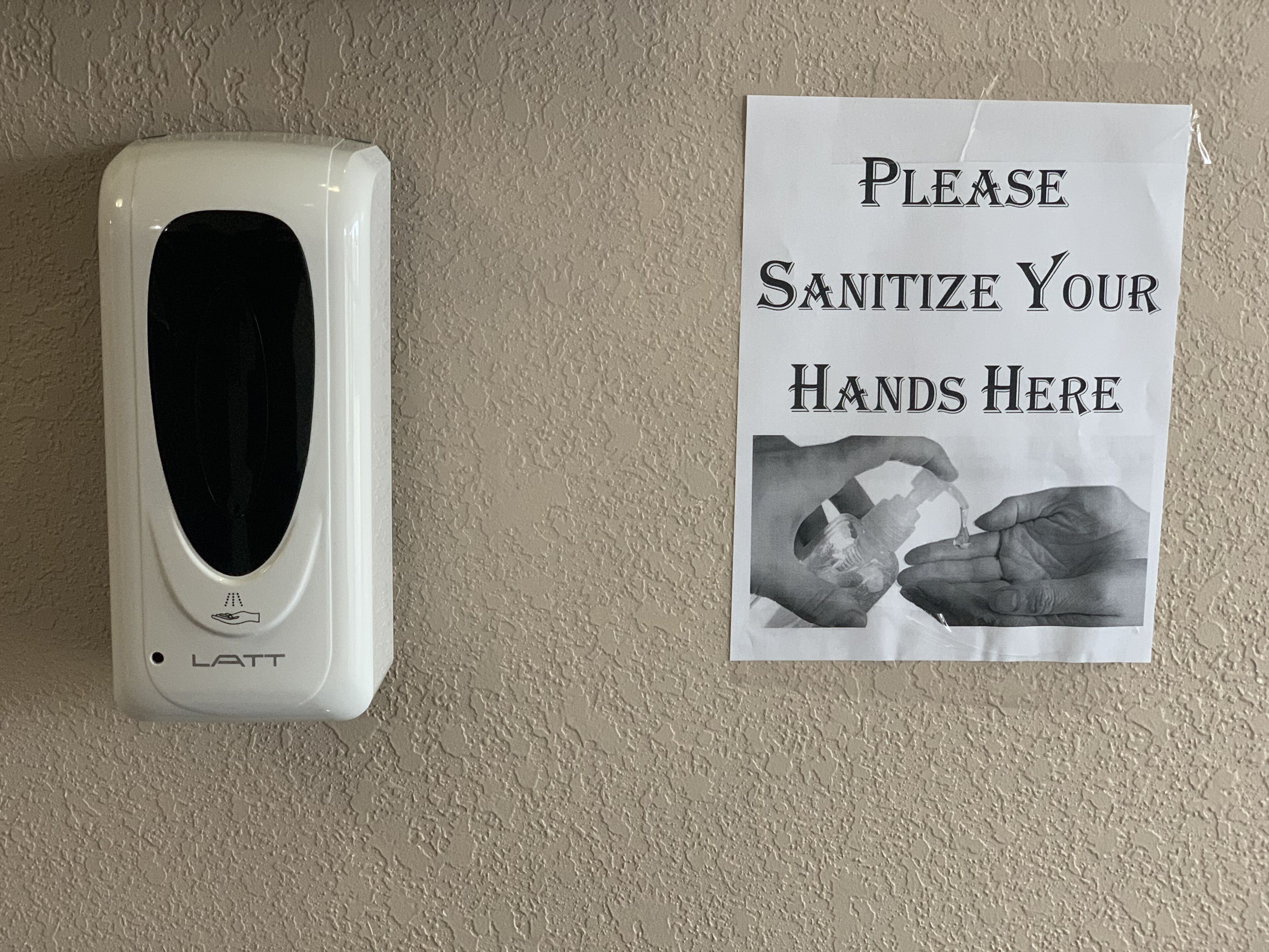A hand sanitizer dispenser and a sign instructing to sanitize hands.
