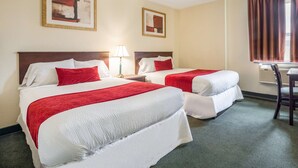 A hotel room with two beds, each with white bedding and red accents, a bedside table with a lamp, and a window with curtains. - Knights Inn Orillia (Orillia)