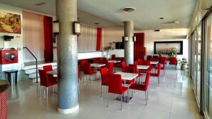 A spacious dining area with red chairs and white tables, large pillars, and a modern ceiling design. - Hotel Sacramora (Rimini)