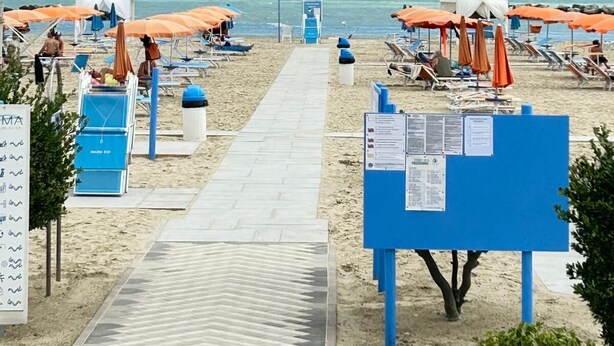 A beach with rows of sun loungers and umbrellas, a lifeguard tower, and a clear view of the sea. - Hotel Sacramora (Rimini)