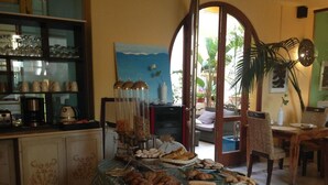 Un comedor con una mesa lista para una comida, una cocina con electrodomésticos y vistas al exterior a través de un ventanal.