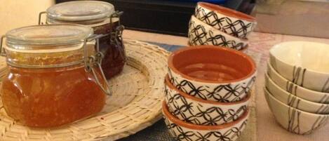 Una mesa con frascos de mermelada, cuencos decorados y recipientes para condimentos.