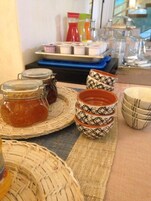Un tavolo con barattoli di marmellata, ciotole decorate e contenitori per condimenti.