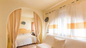 Una habitación con cama, sofá y ventana con cortinas.