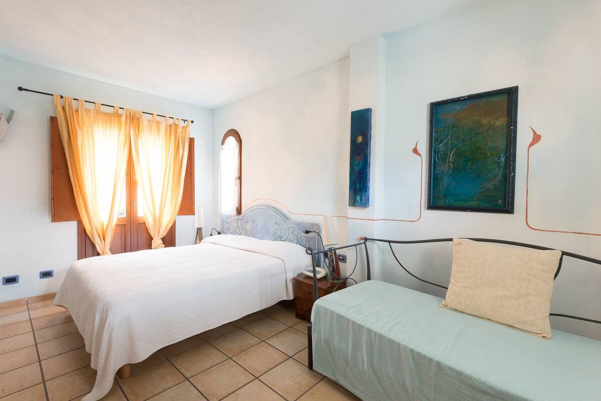 A bedroom with two beds, a nightstand, a mirror, and artwork on the walls.