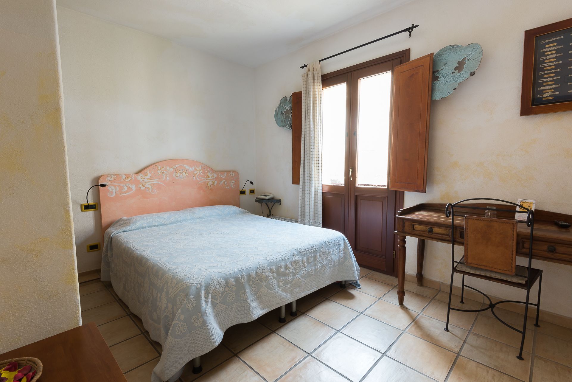 A bedroom with a bed, a desk, and a chair.
