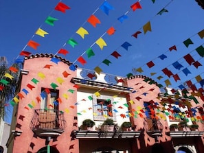 A building with a pink facade, balconies, and a clear blue sky.