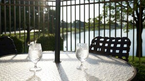 Dos copas de vino vacías sobre una mesa redonda con barandilla de metal y vista a un lago.