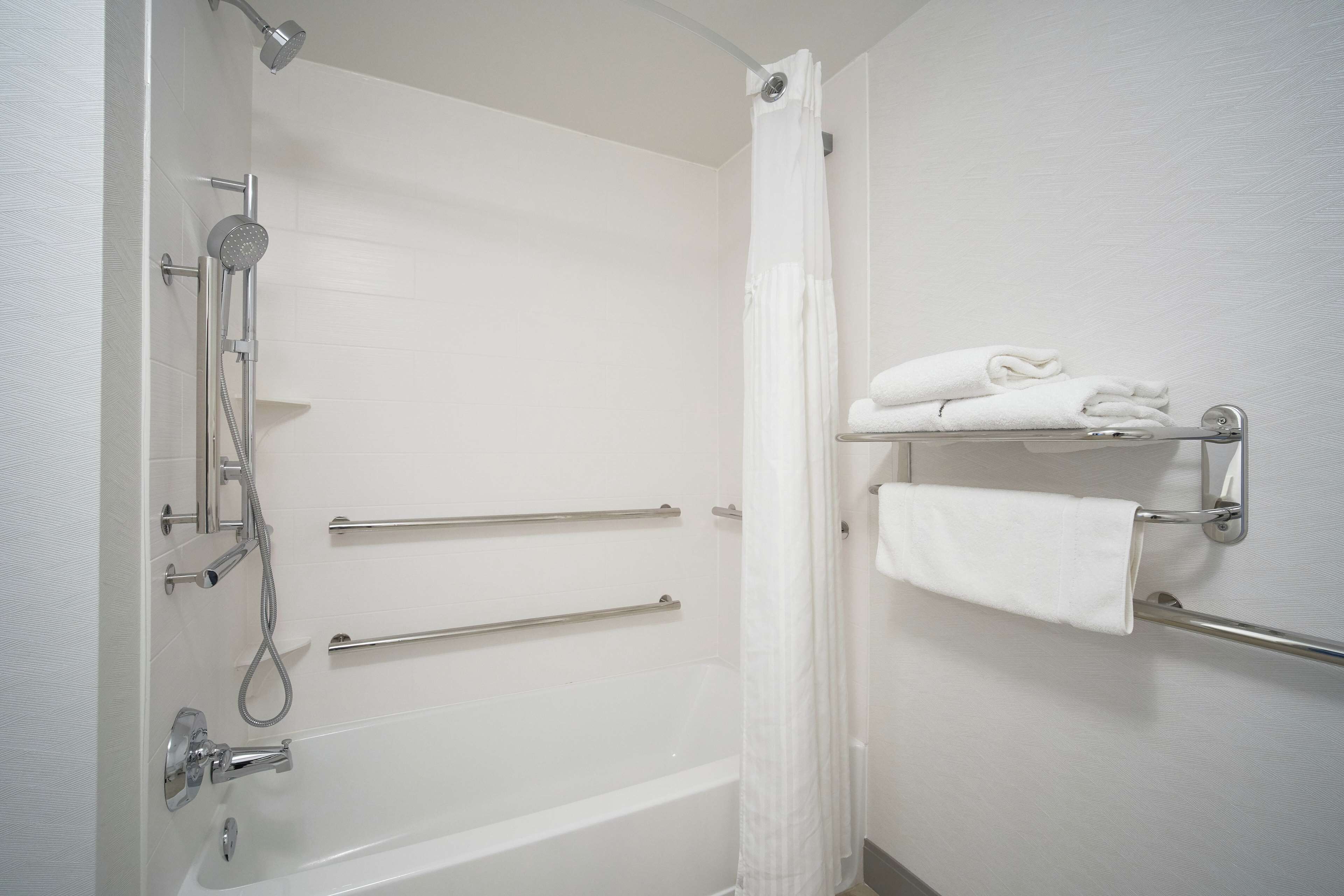 A bathroom with a bathtub, a shower, and a towel rack with folded towels.