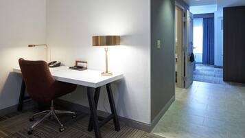 Een hotelkamer met een bureau, stoel, lamp en telefoon.