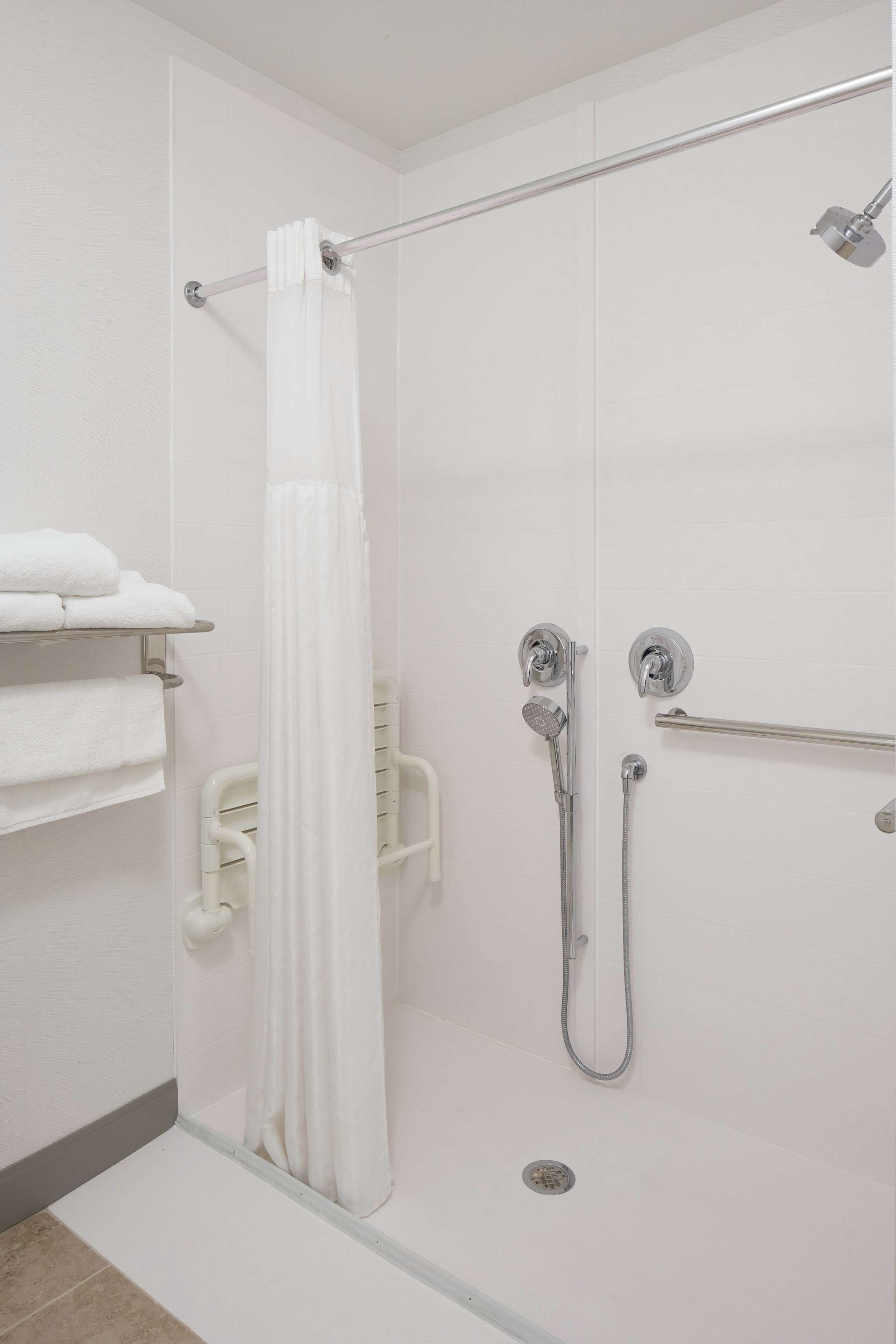 Un espace douche doté d’une porte en verre, d’un porte-serviettes blanc et d’un pommeau de douche.