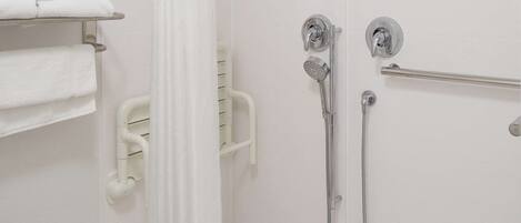 Un espace douche doté d’une porte en verre, d’un porte-serviettes blanc et d’un pommeau de douche.