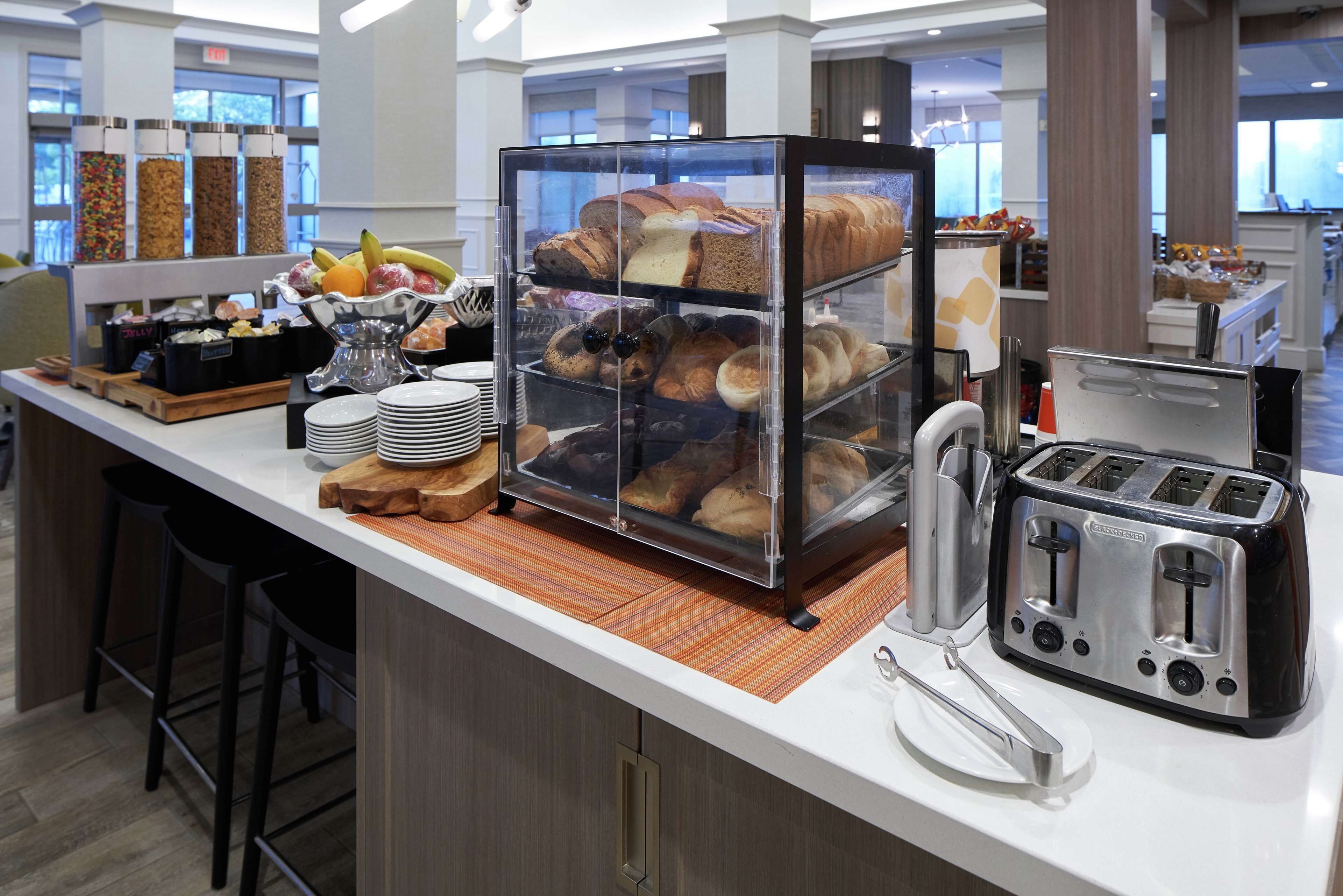 A breakfast bar with a variety of pastries, a fruit display, and a toaster.