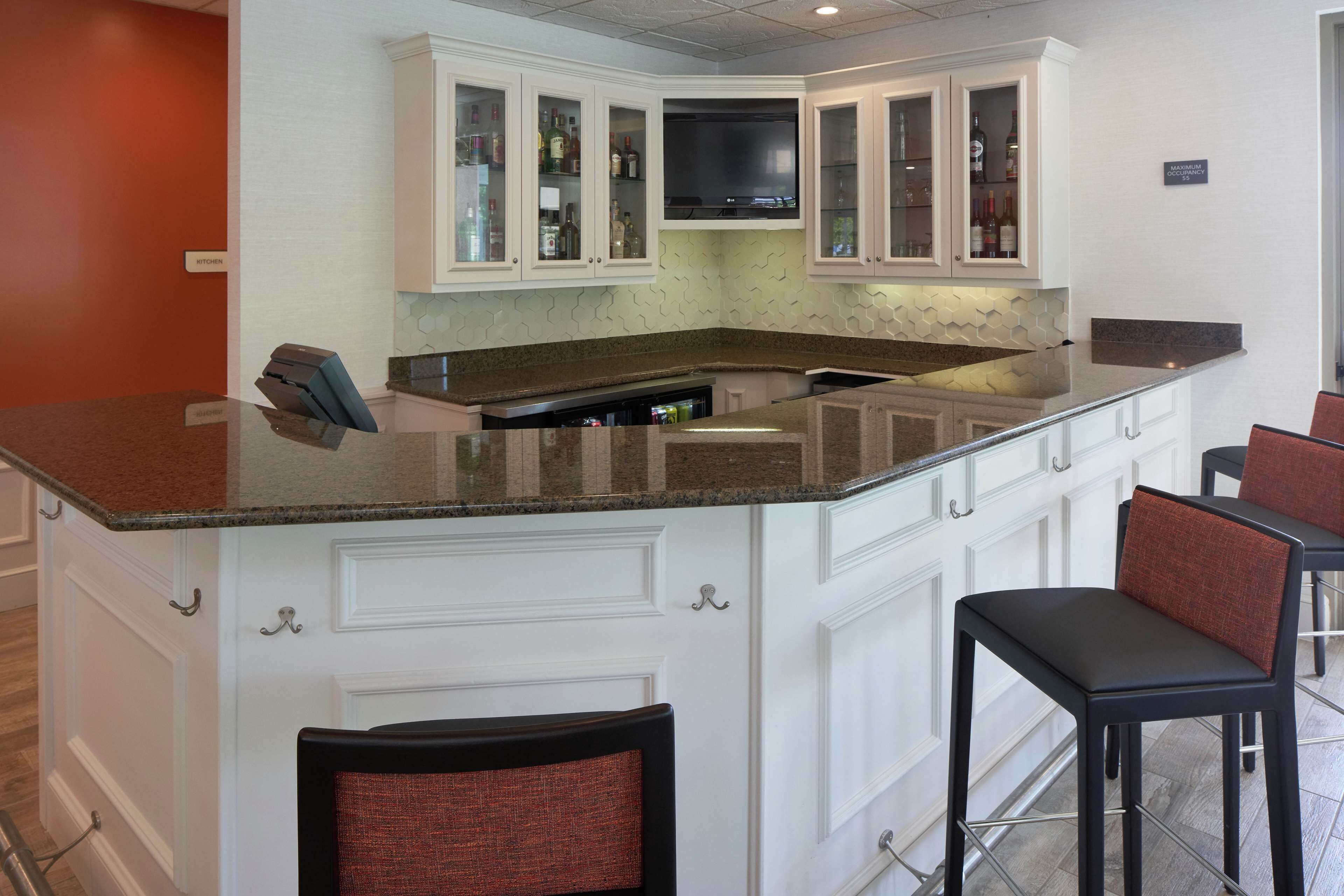 A kitchen with white cabinetry, a granite countertop, and a built-in TV.