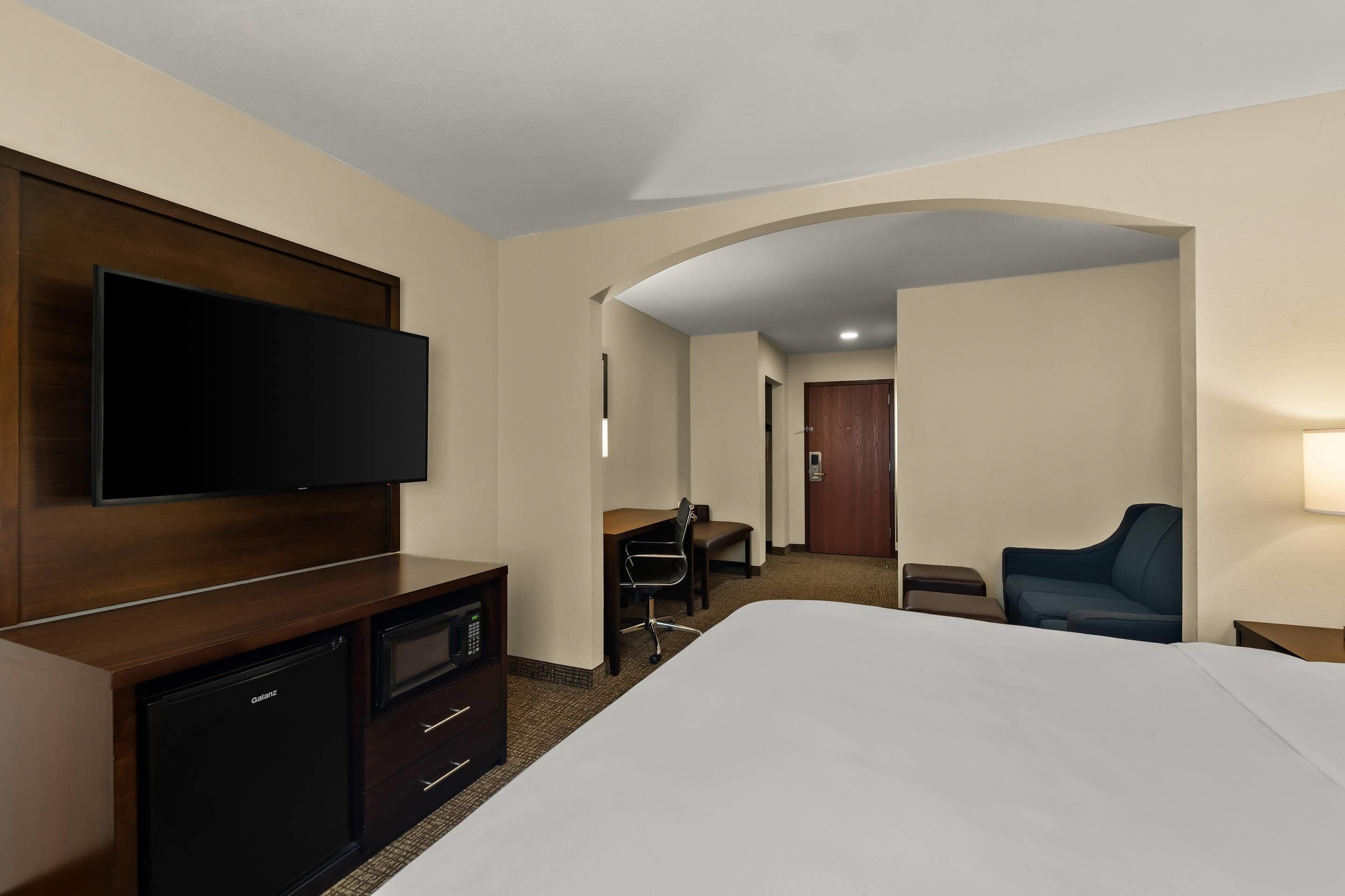 Een hotelkamer met een bed, een televisie, een bureau, een stoel en een bank.