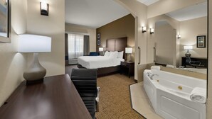 A hotel room with a bed, a desk, a chair, a bathtub, and a large mirror.