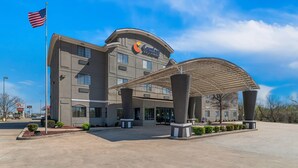A Comfort Inn hotel with a covered entrance, American flag, and a clear blue sky.
