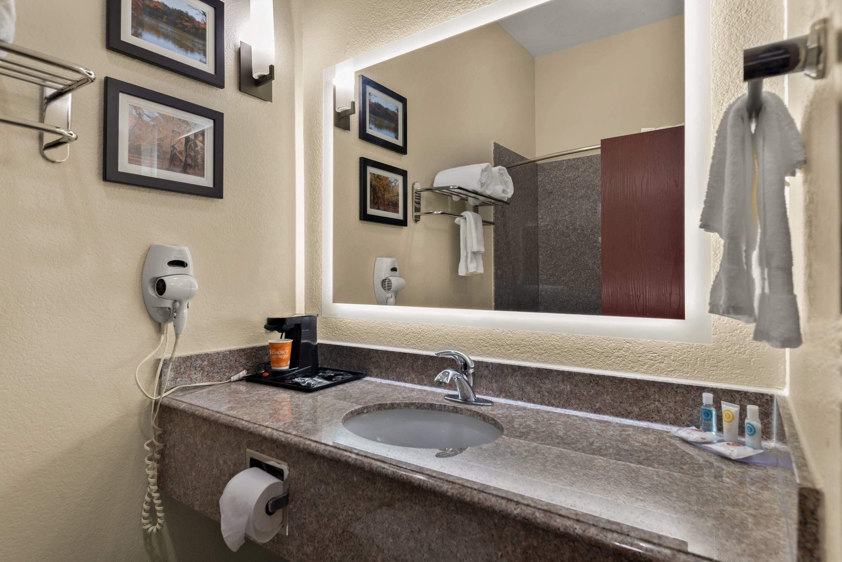 A bathroom with a sink, mirror, towel rack, framed pictures, and a hairdryer.