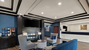A lobby with a reception desk, seating area, and a flat-screen TV.
