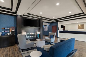 A lobby with a reception desk, seating area, and a flat-screen TV.