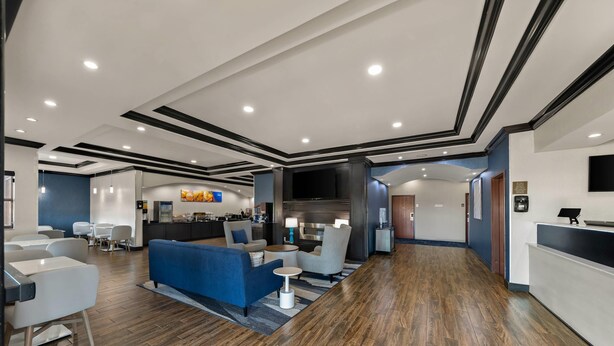 A modern hotel lobby with a reception desk, seating area, and a bar.