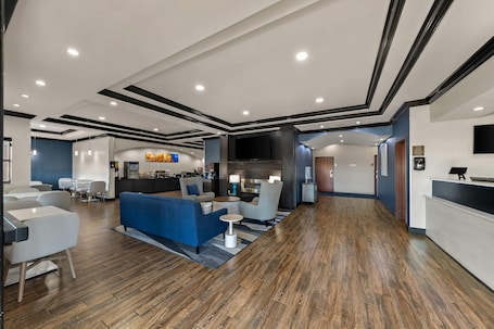 A modern hotel lobby with a reception desk, seating area, and a bar.. Comfort Inn & Suites Atoka