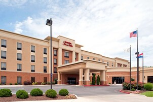 Un hotel Hampton Inn & Suites con fachada de ladrillo, un acceso cubierto y un estacionamiento.