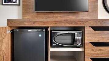 A kitchen with a black refrigerator, a microwave, and a flat-screen TV mounted above the counter.