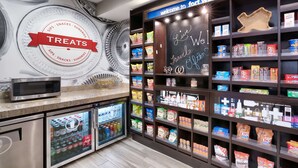 A self-service snack and drink station with a variety of products on shelves and refrigerated beverages. - Hampton Inn & Suites Ft. Worth-Burleson (Burleson)