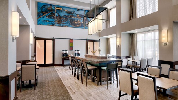 A spacious hotel lobby with a central bar area, multiple seating arrangements, and a large abstract painting on the wall. - Hampton Inn & Suites Ft. Worth-Burleson (Burleson)