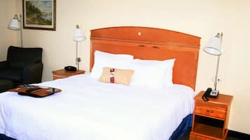 Habitación de hotel con una cama grande, dos mesitas de noche, una silla y un cuadro en la pared.