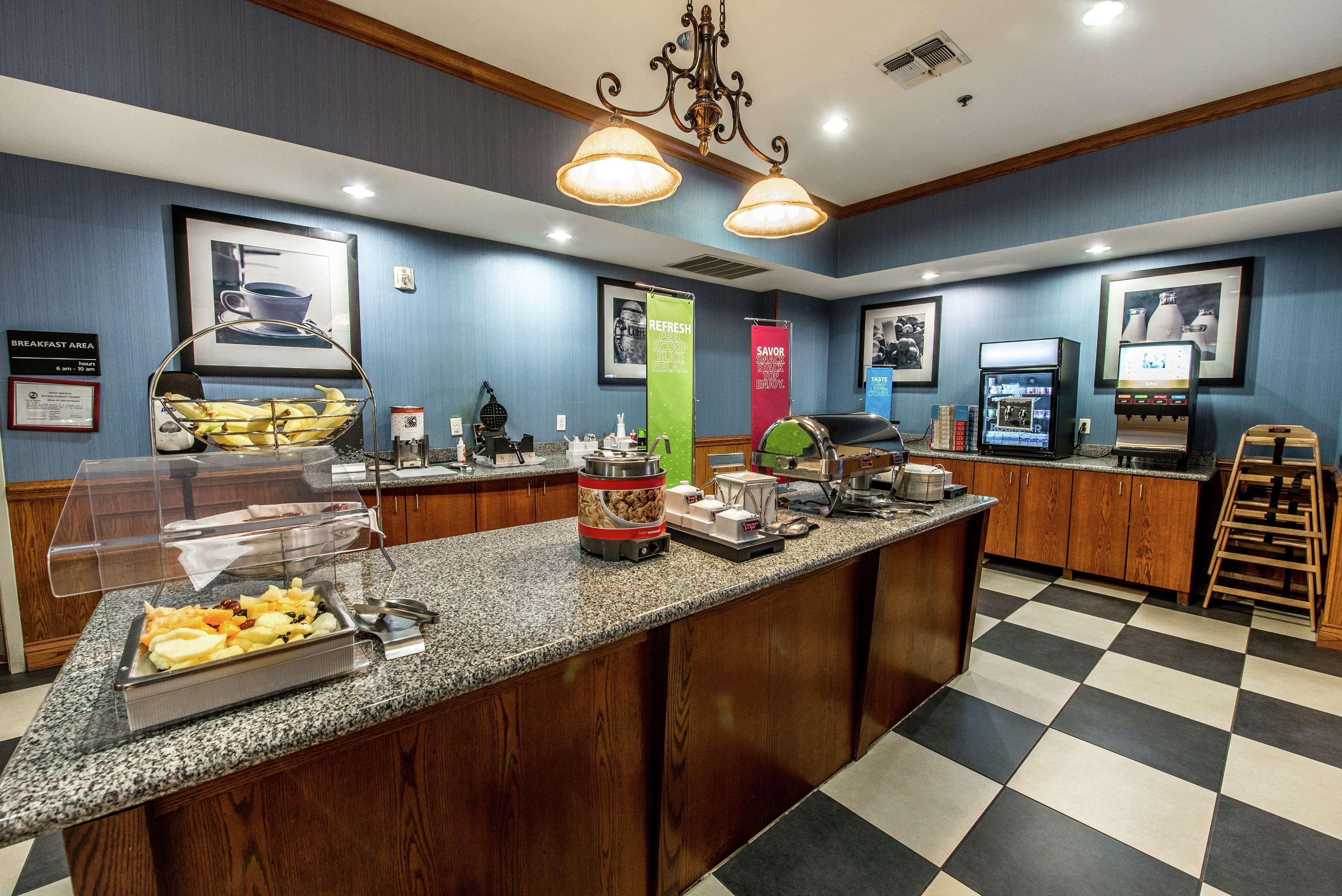 A breakfast bar with a variety of food items, a coffee machine, and a beverage dispenser.