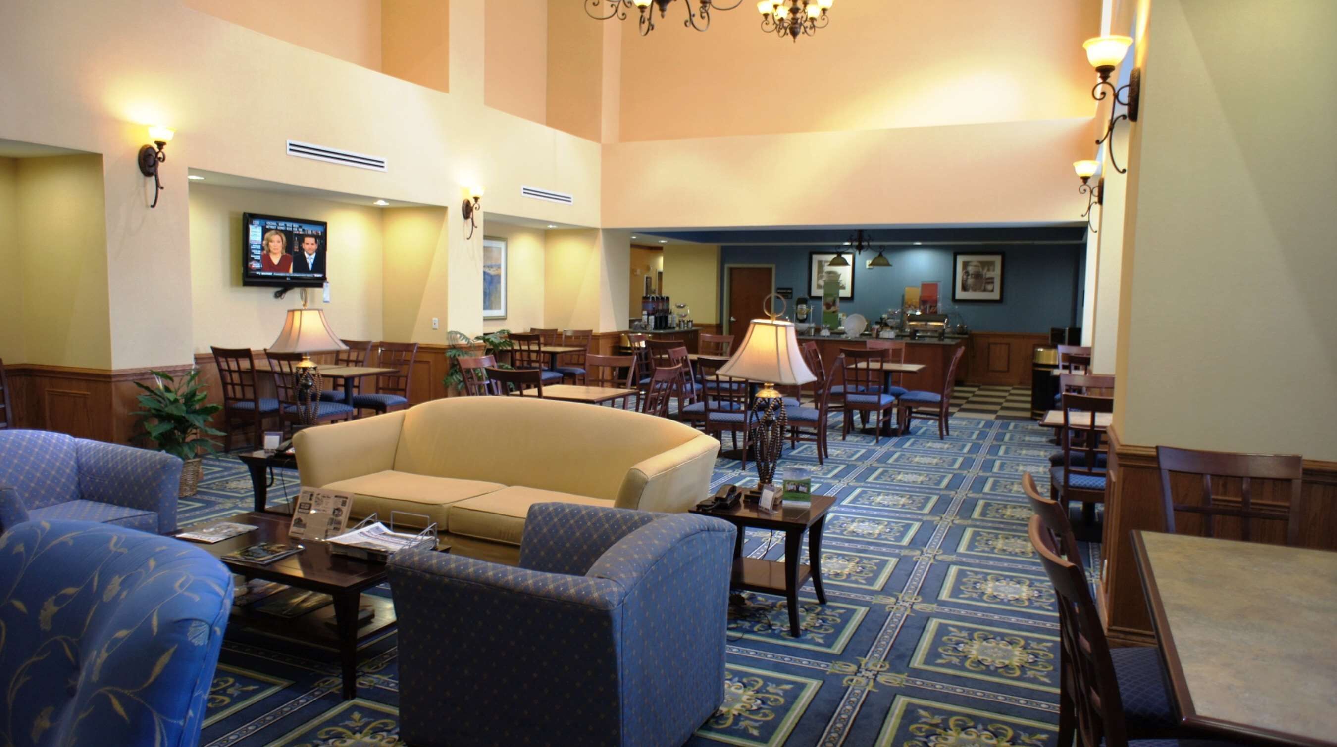 A hotel lobby with a central seating area, multiple tables, and a bar.