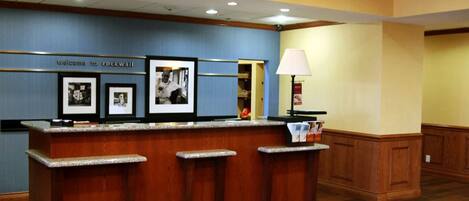 A reception desk with framed photos, a lamp, and a sign that reads "Welcome to rockwall."