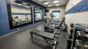 Een sportschool met trainingsapparatuur, waaronder loopbanden, een bank en gewichten.