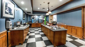 Een hotelkeuken met geruit vloer, houten kasten en een centraal eiland met etenswaren.