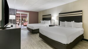 A hotel room with two beds, a desk with a TV, and a window with a view of the outside. - Eisenhower Hotel & Conference Center (Gettysburg)