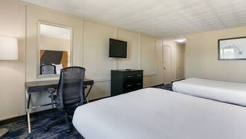 Una habitación de hotel con cama, escritorio, silla, televisor y cómoda.