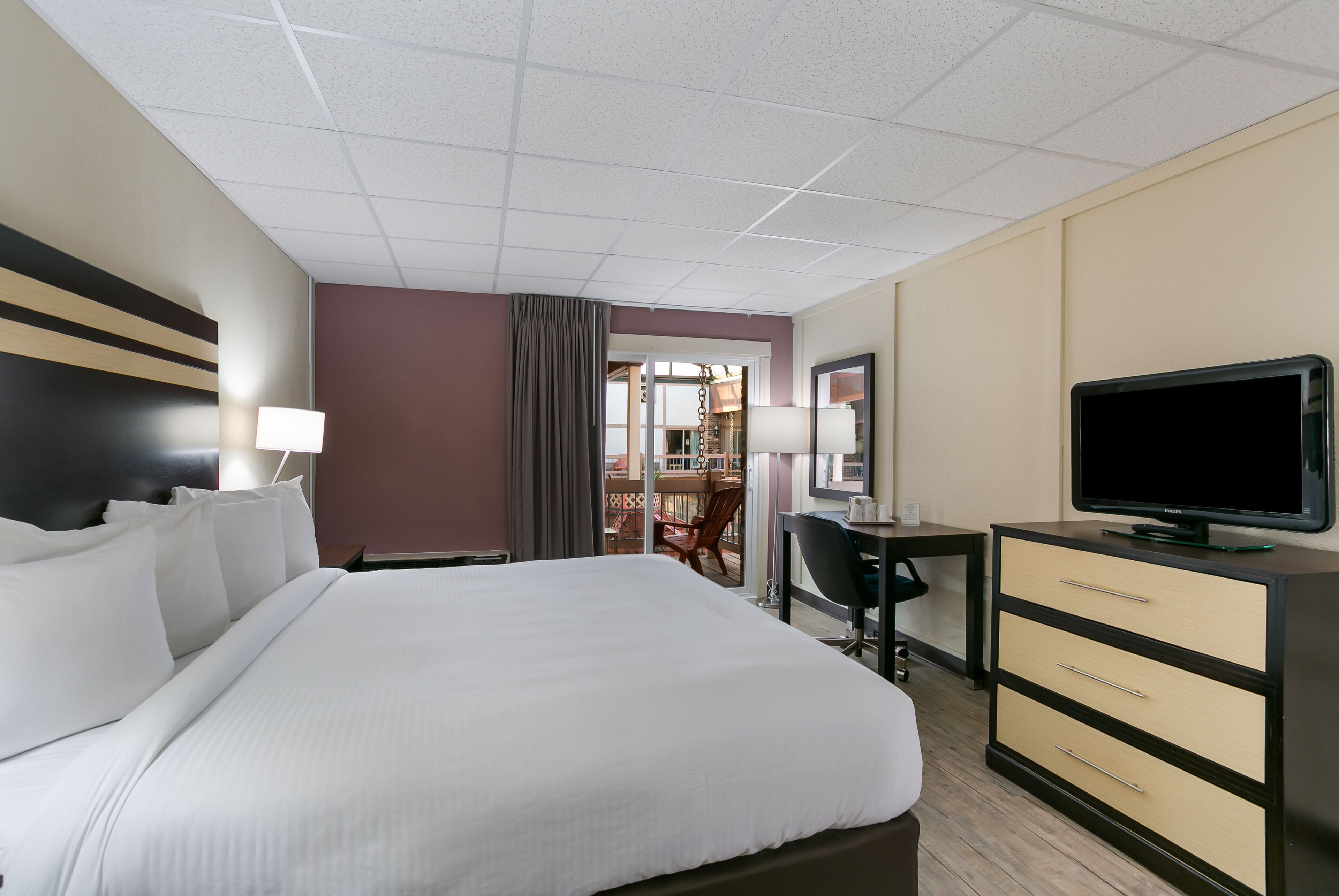 A hotel room with a large bed, a desk, a television, and a wardrobe.