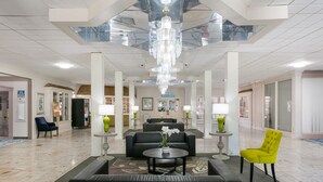 A spacious lobby with a chandelier, seating areas, and a reception desk. - Eisenhower Hotel & Conference Center (Gettysburg)