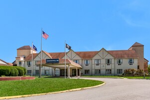 Um hotel com entrada coberta, bandeiras americanas e uma placa com a inscrição 'EISHAWER INN'.