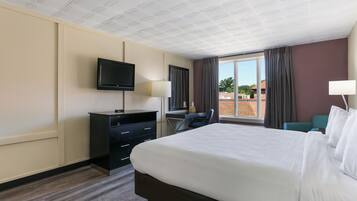 A hotel room with a bed, a desk, a television, and a window with curtains.