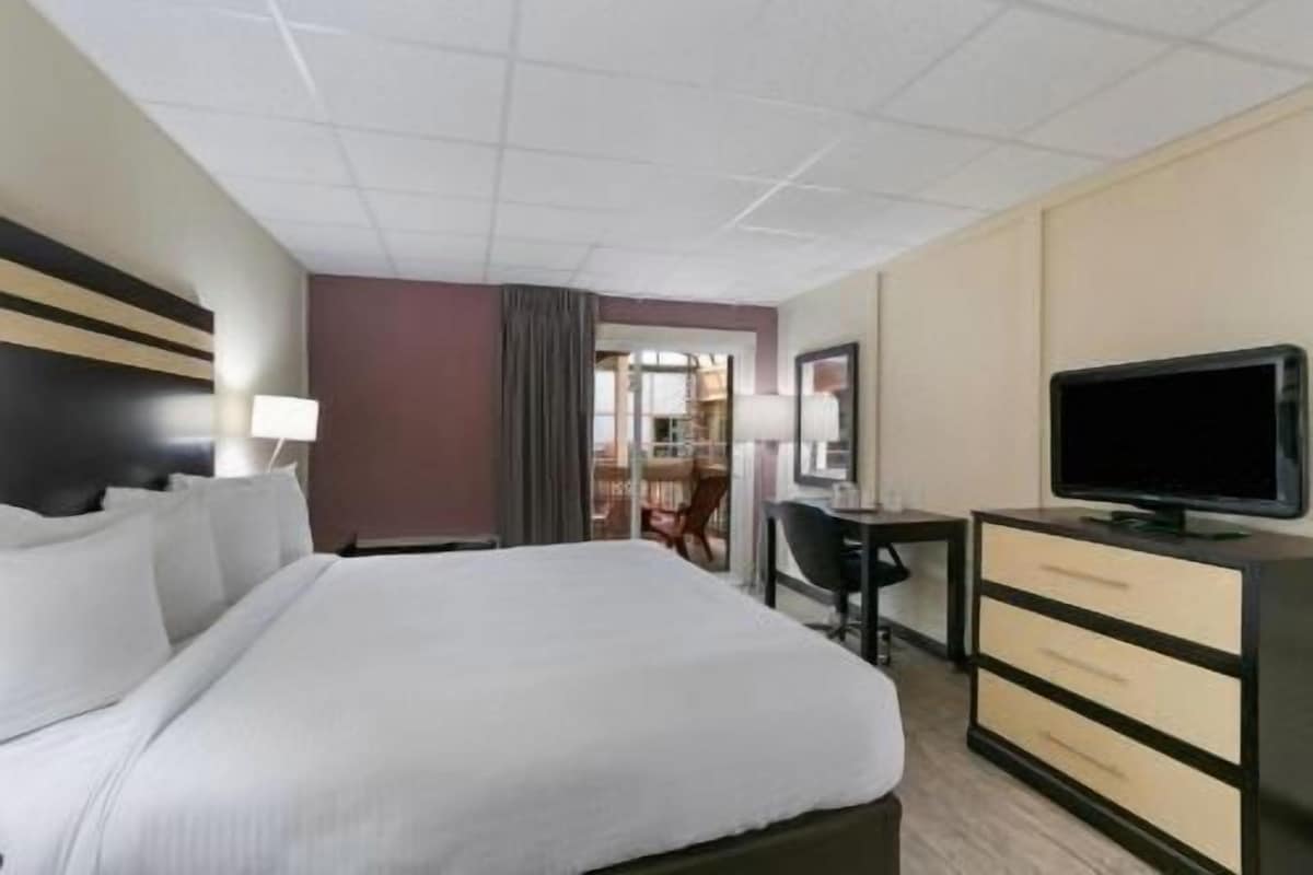 A hotel room with a bed, a desk, a television, and a chair.