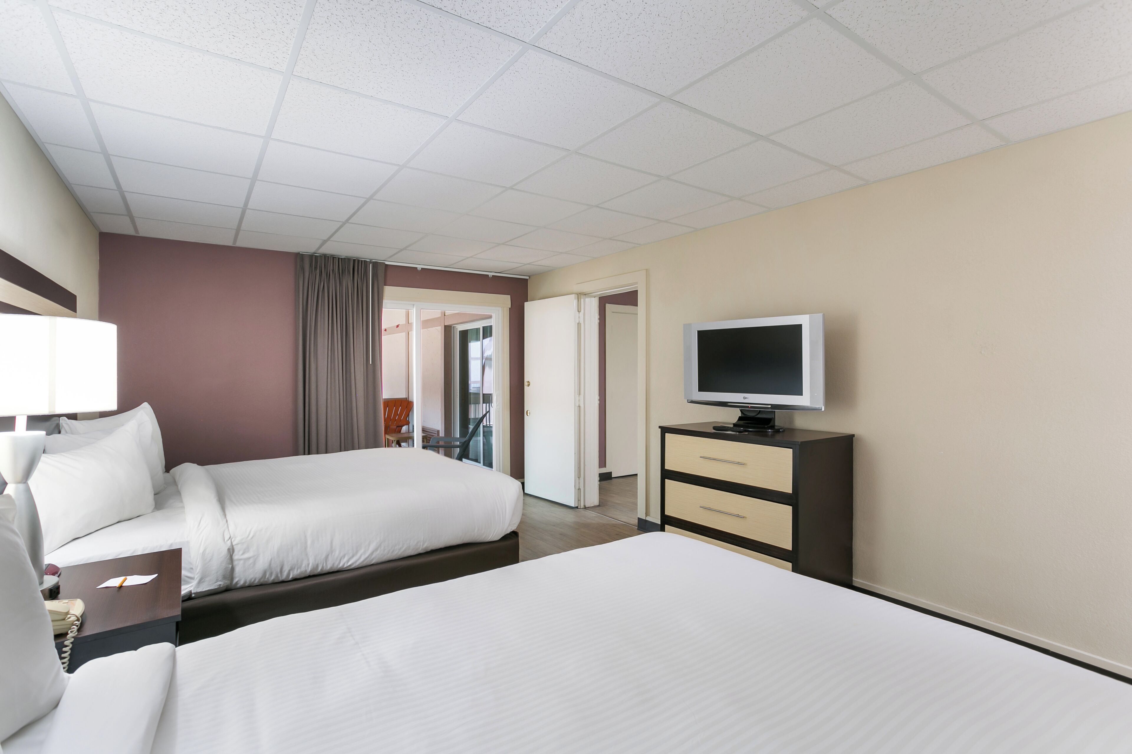 A hotel room with two beds, a television, a desk, and a chair.