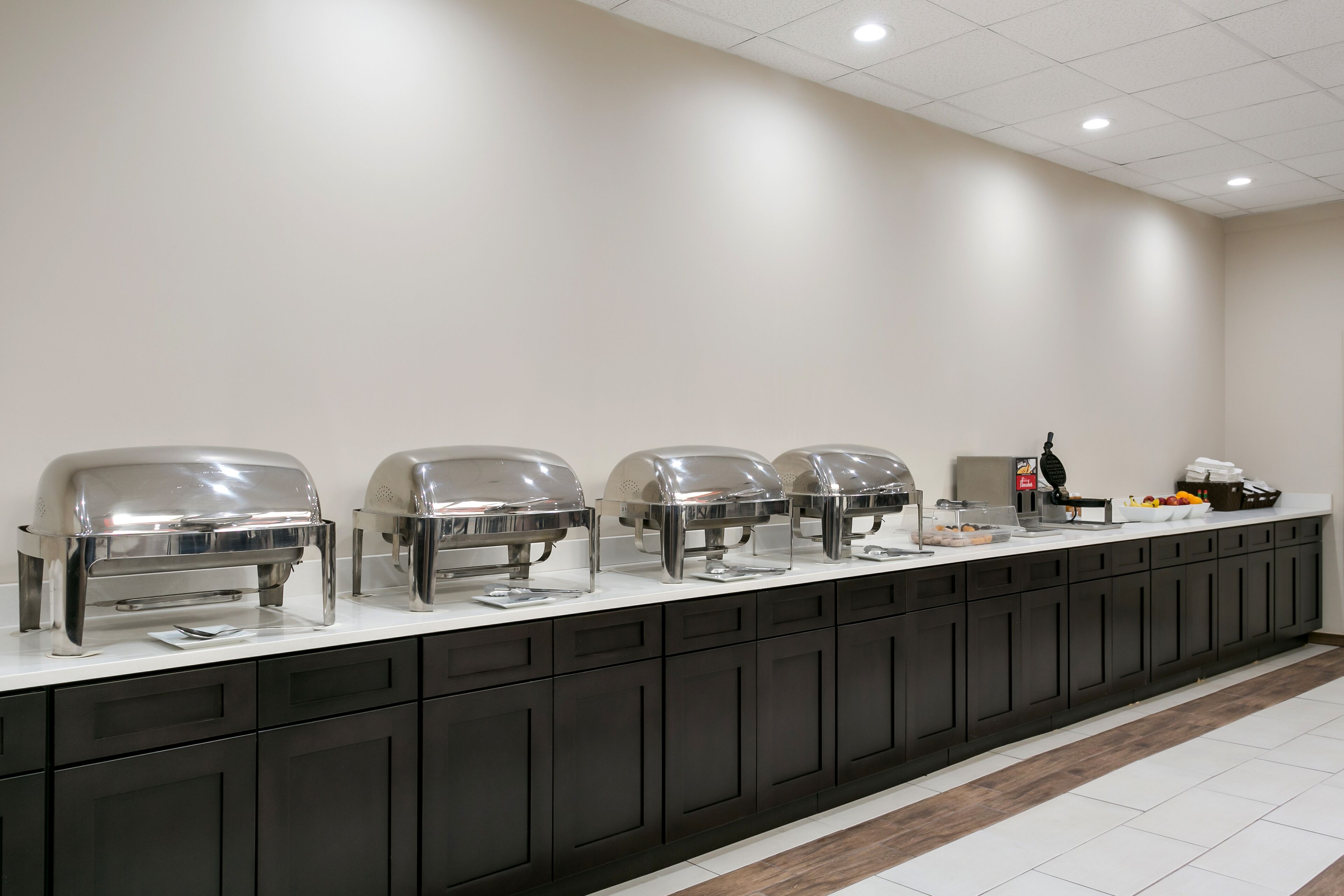 A buffet setup with three covered food stations and a beverage dispenser.