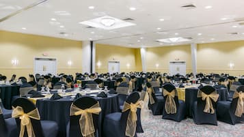 Un amplio salón de conferencias con filas de mesas y sillas, cada una con cubierta negra y fajín dorado.