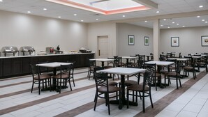 A spacious cafeteria with multiple tables and chairs, a counter with food service equipment, and a skylight above. - Eisenhower Hotel & Conference Center (Gettysburg)