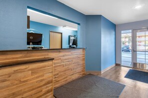 Zona de recepción con un mostrador de madera, una computadora Dell y una puerta que da al exterior.